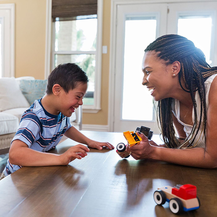 The young boy with Down Syndrome enjoys play therapy with his therapist at home.
